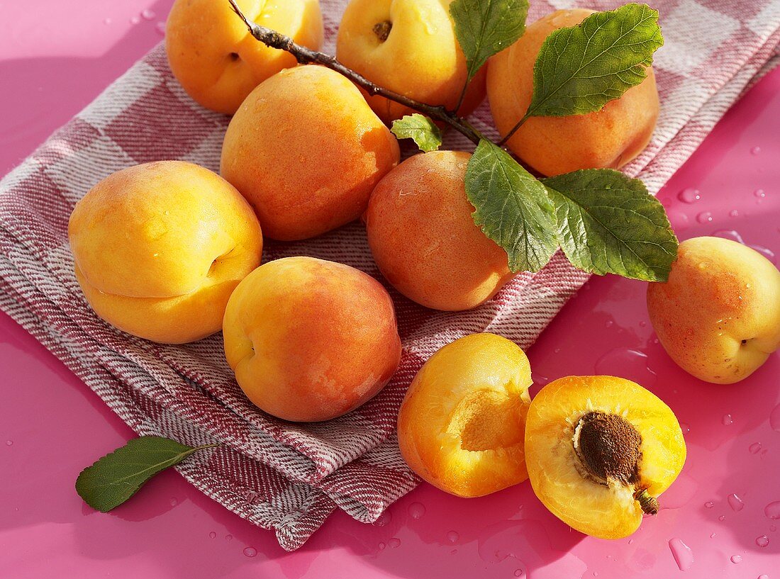 Mehrere frische Aprikosen, ganz und halbiert
