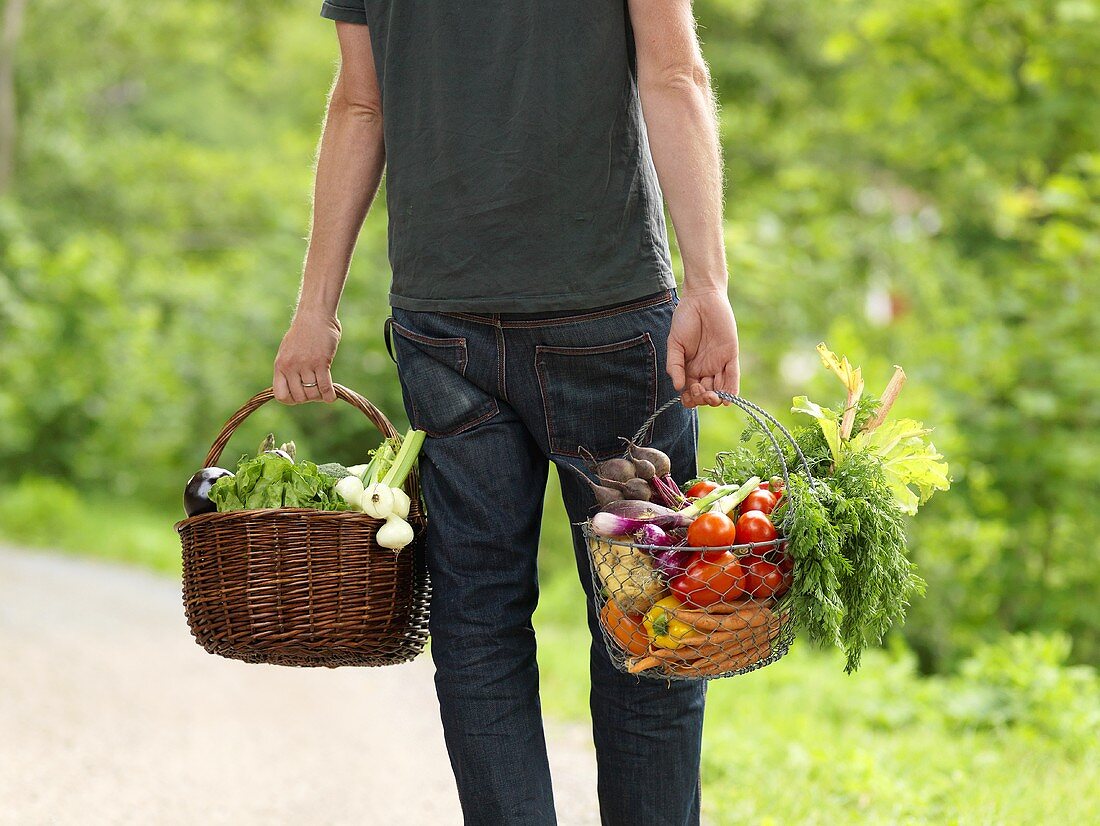 Mann trägt zwei Gemüsekörbe