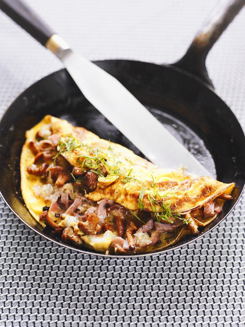 Ham and chanterelle omelette in frying pan