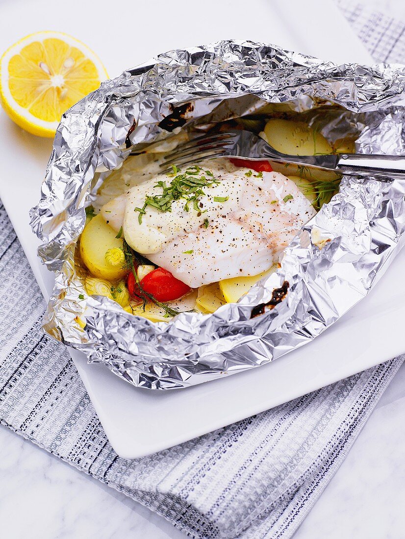 Fish fillet and vegetables in aluminium foil