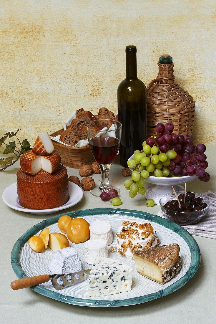 Cheese still life with red wine, grapes, nuts, bread & olives