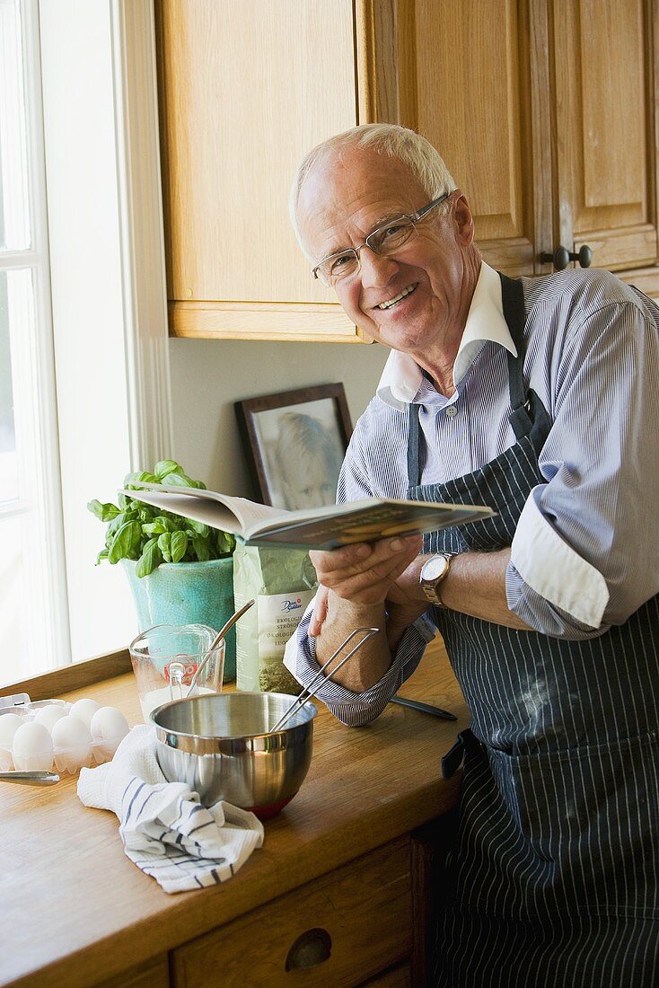 Älterer Mann beim lesen im Rezeptbuch