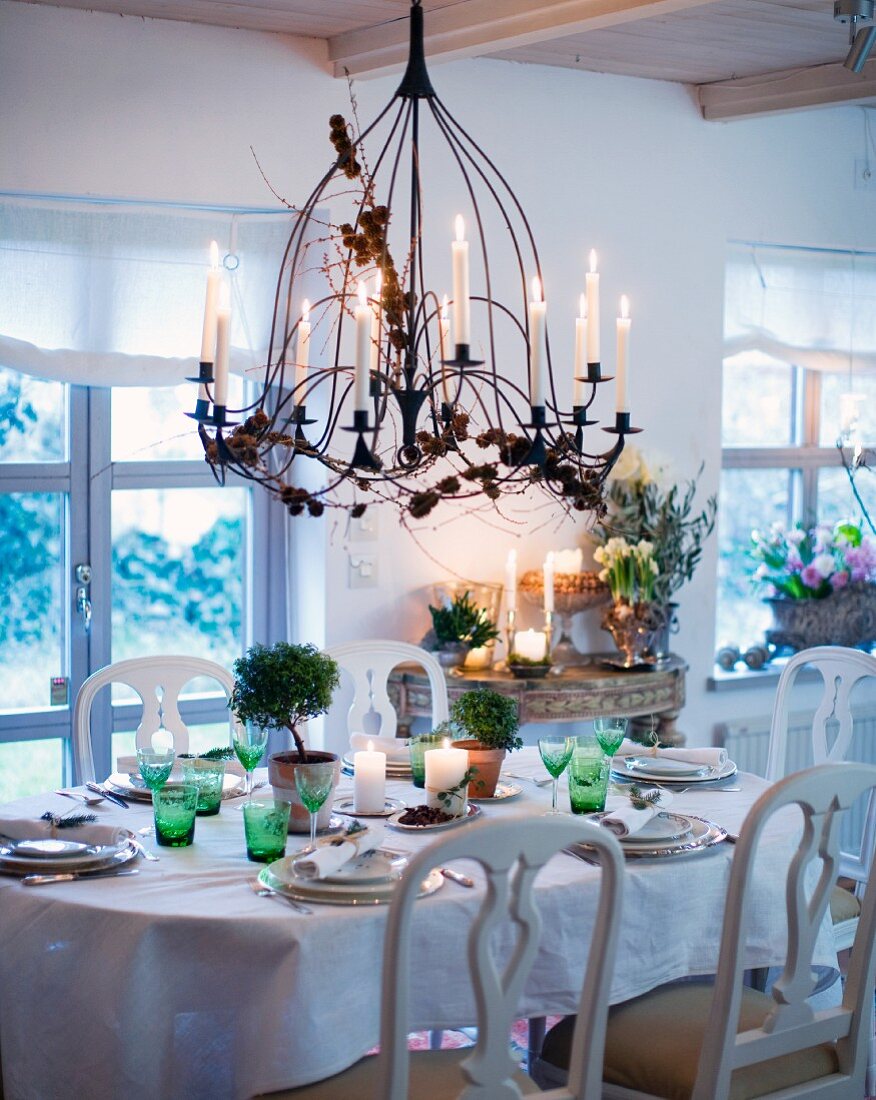Festlich gedeckter Esstisch eines Landhauses mit großem, von der Decke hängendem Kerzenleuchter