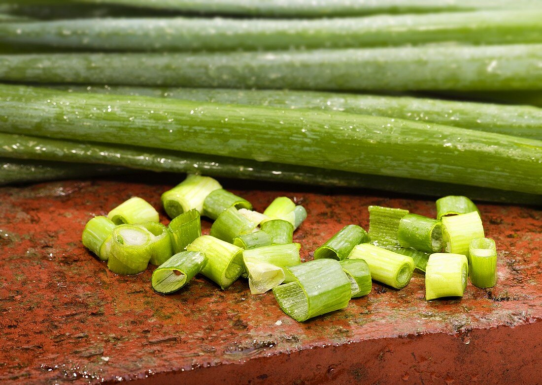 Spring onions, partly sliced, on brick