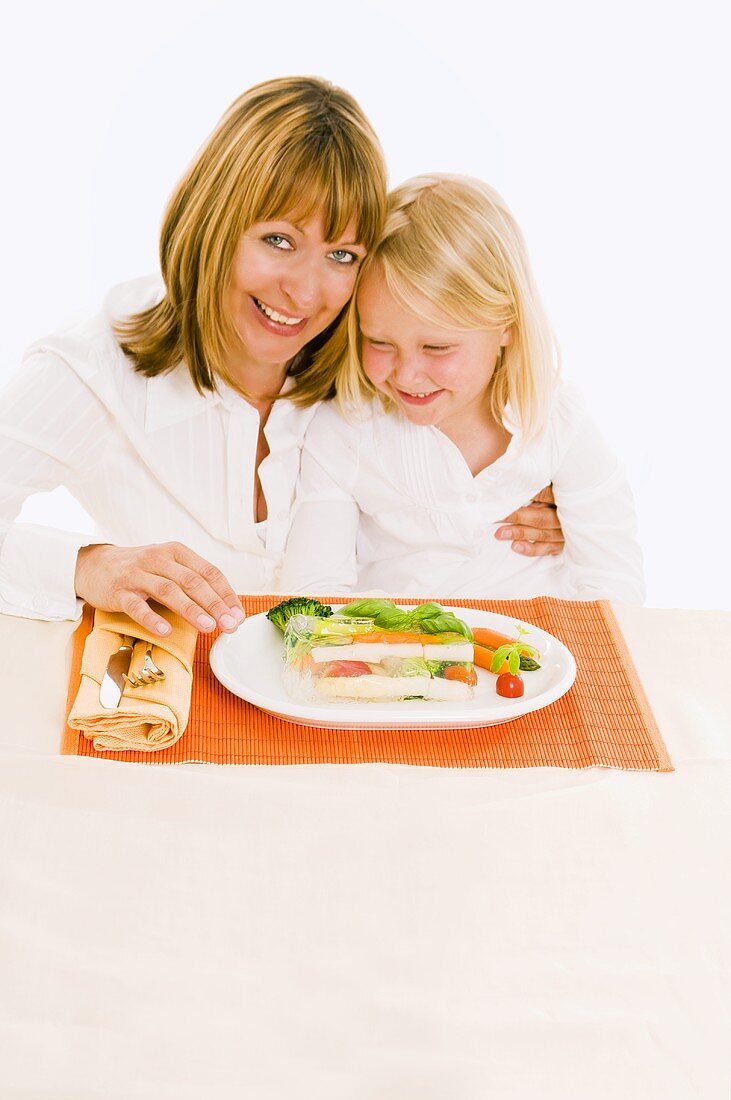 Mutter und Tochter sitzen am Tisch vor Gemüseterrine
