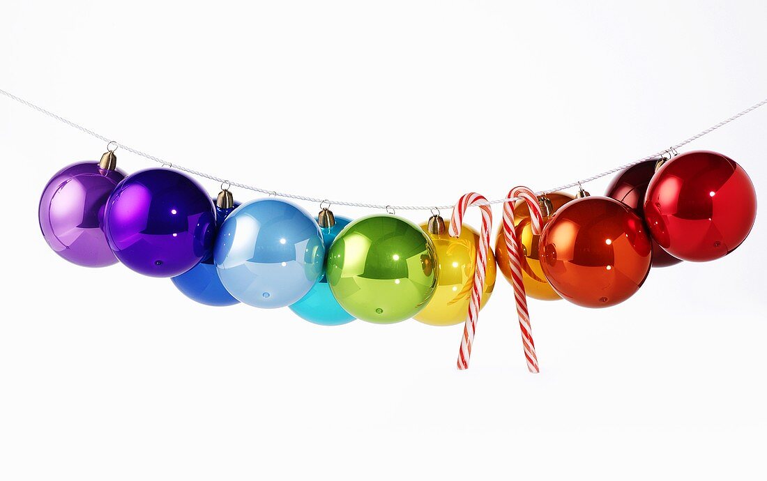 Shiny, coloured Christmas baubles & candy canes on washing line