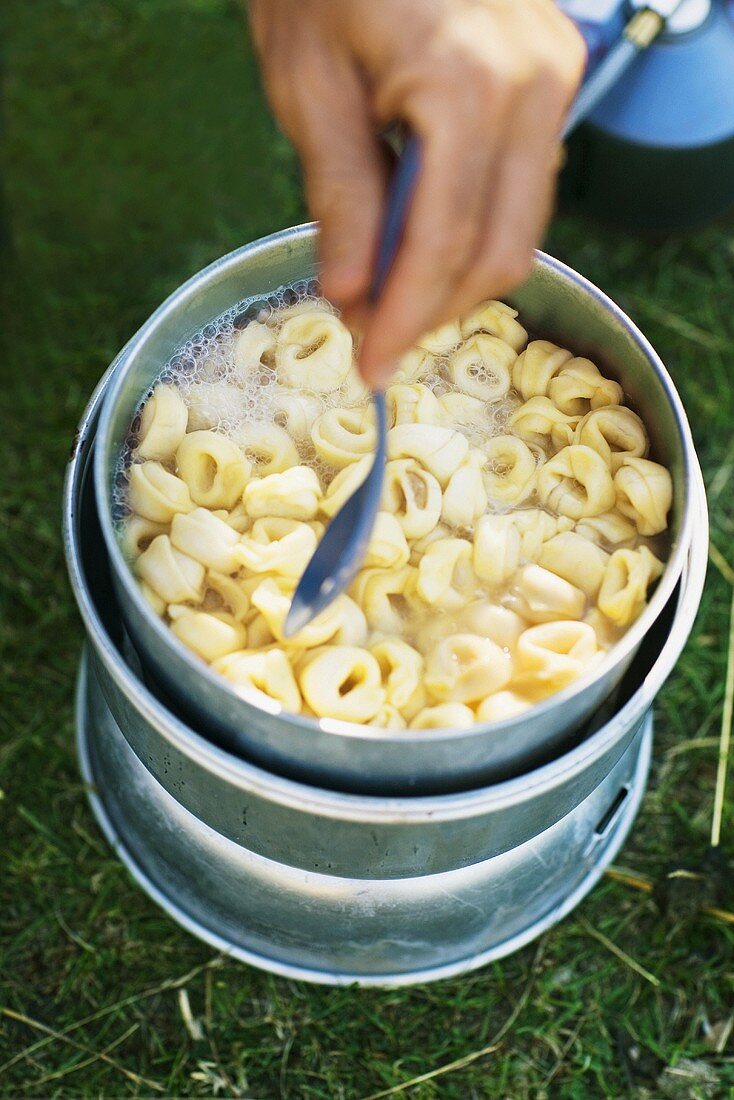 Man cooking tortellini on a camping stove