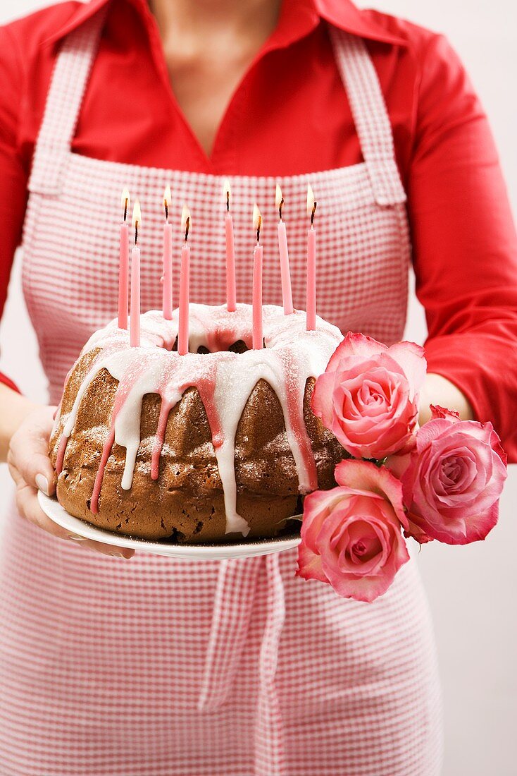 Frau hält Napfkuchen und Rosen zum Geburtstag