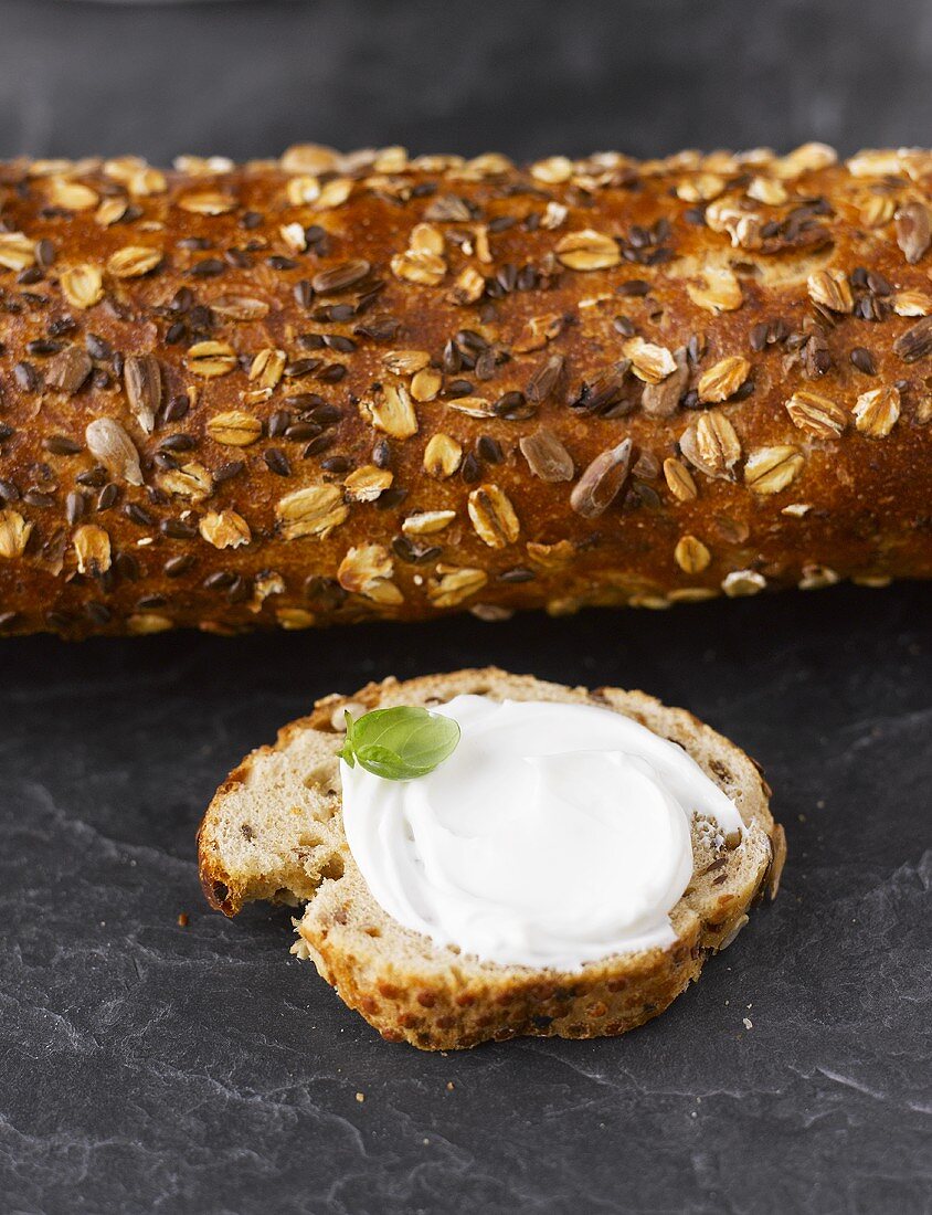 Multigrain baguette and baguette slice with cream cheese and basil leaf