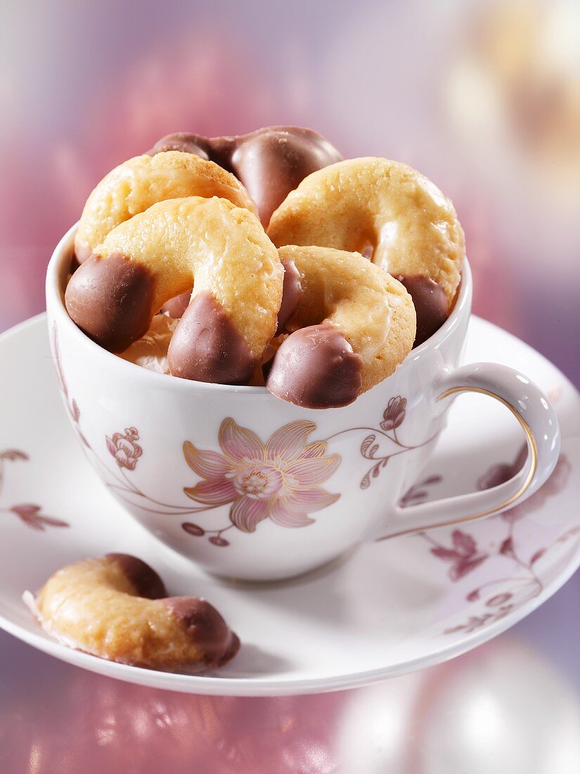 Chocolate-dipped vanilla cresecents in a cup and saucer
