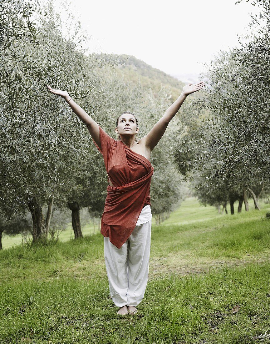 Frau macht Yogaübung im Olivenhain