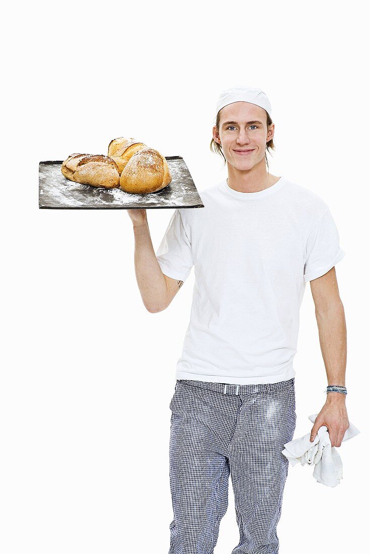 Baker holding a baking tray with freshly baked bread