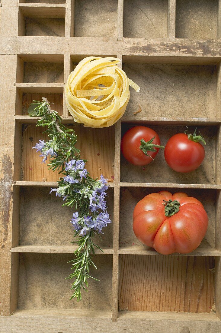 Ribbon pasta, tomatoes and rosemary in type case
