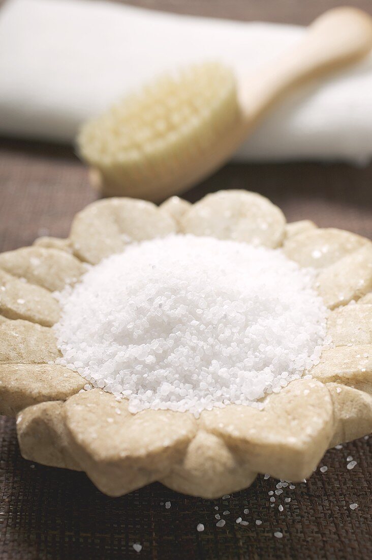 Bath salts in flower-shaped dish, brush in background