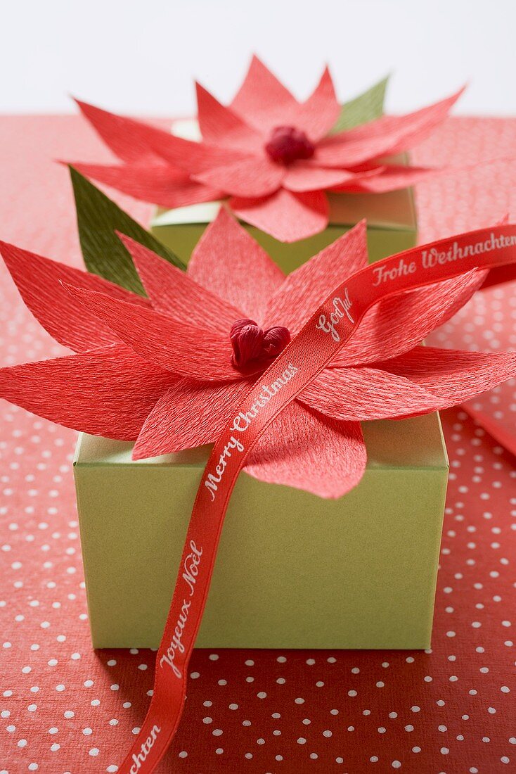 Two Christmas parcels decorated with red paper flowers