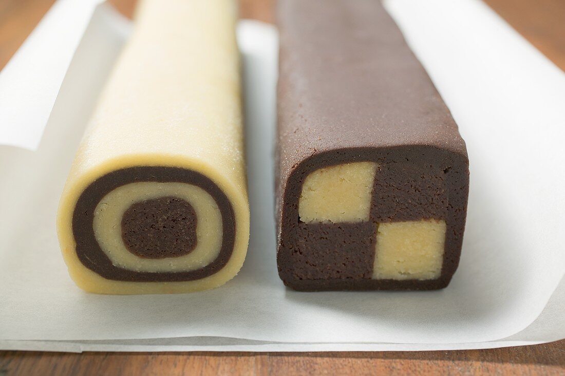 Two rolls of chocolate and plain dough on baking parchment