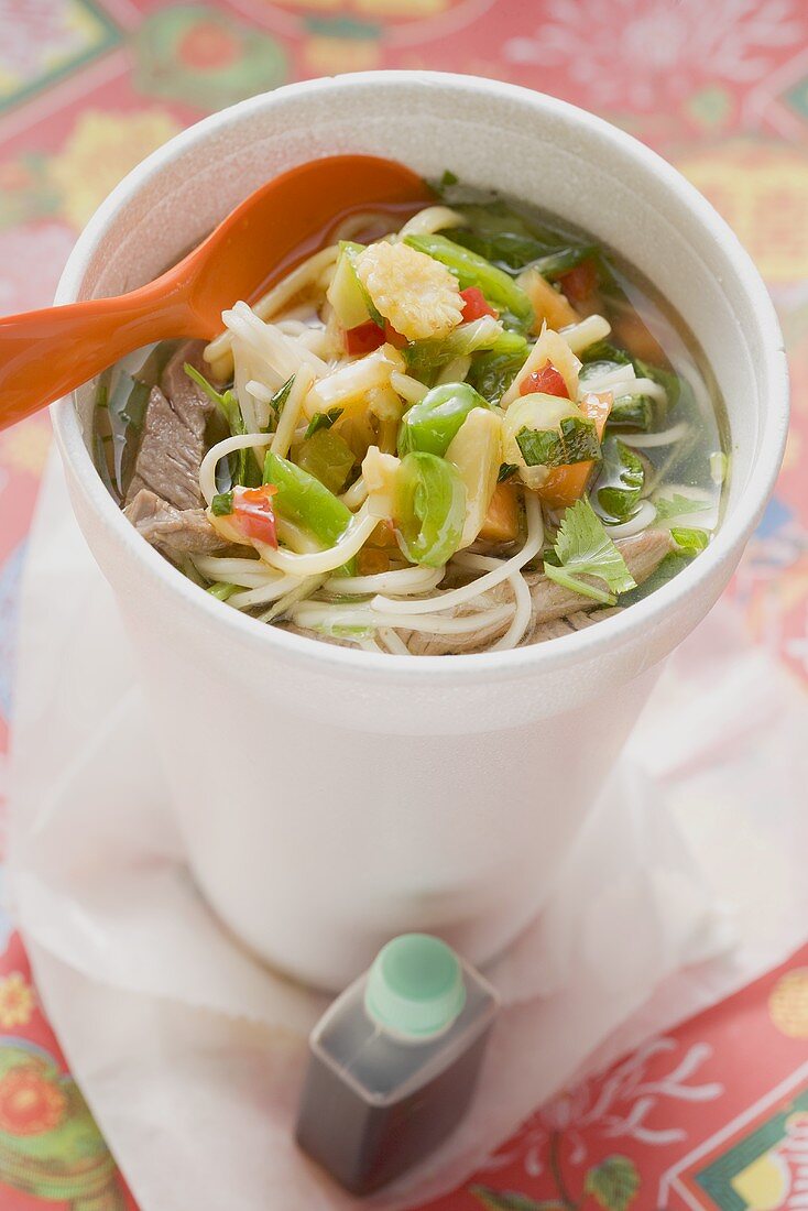 Noodle soup with beef and vegetables in cup, soy sauce