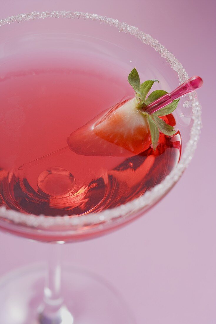 Martini mit Likör und Erdbeere im Glas mit Zuckerrand