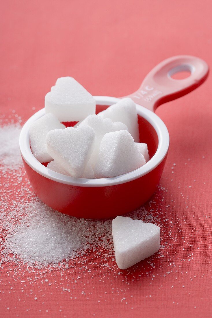 Heart-shaped sugar lumps in red measuring cup