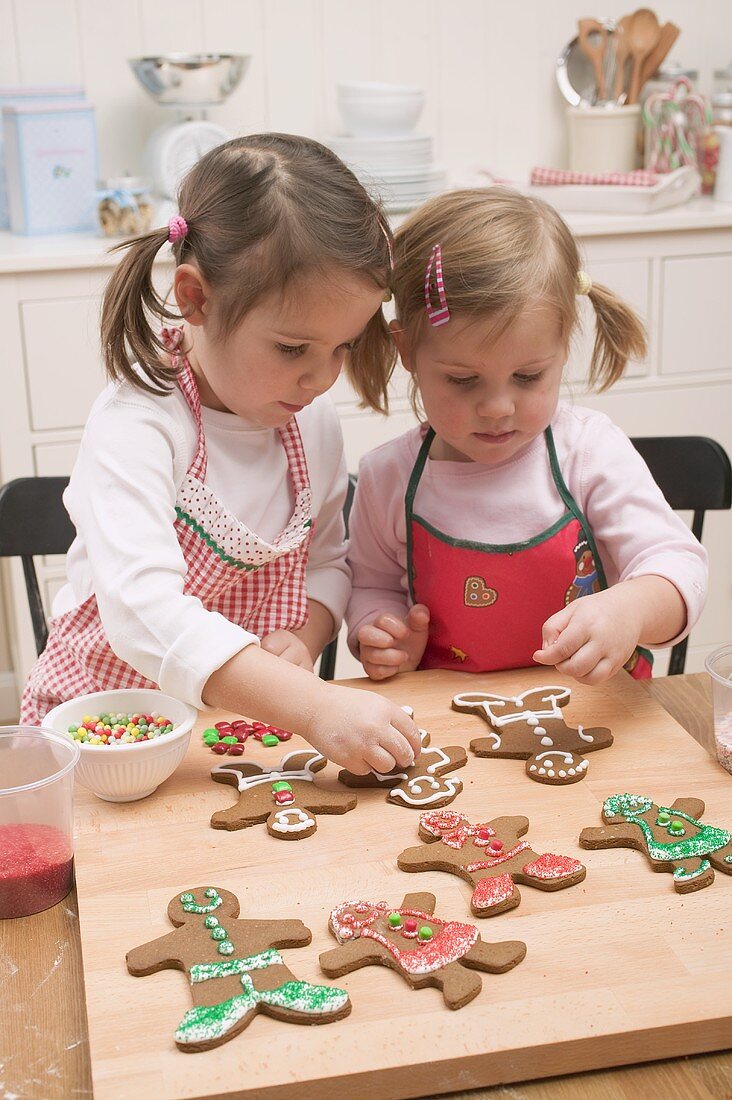 Zwei kleine Mädchen verzieren Lebkuchenfiguren