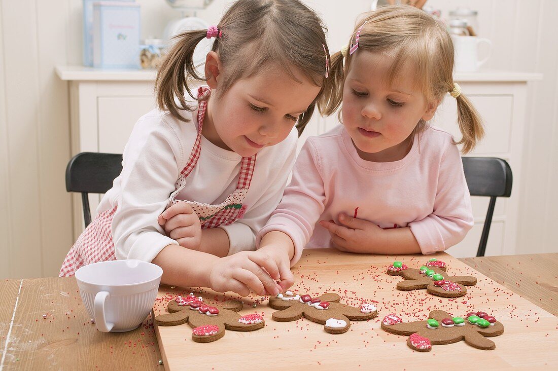 Zwei kleine Mädchen verzieren Lebkuchenfiguren