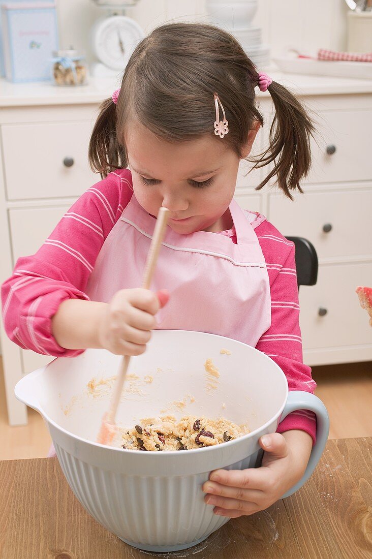 Small girl stirring mixture in mixing bowl