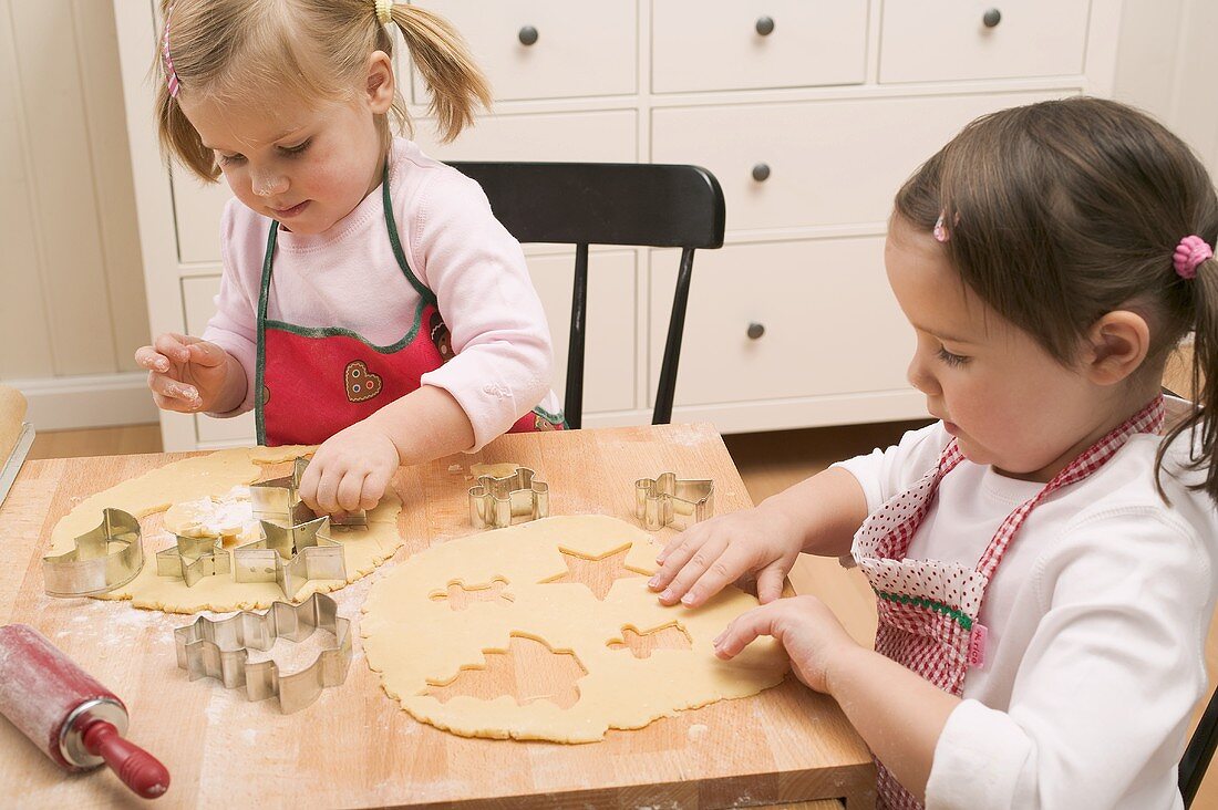 Two small girls cutting out biscuits