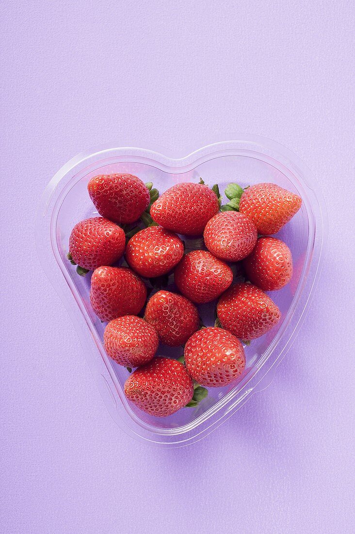 Frische Erdbeeren in herzförmiger Plastikschale