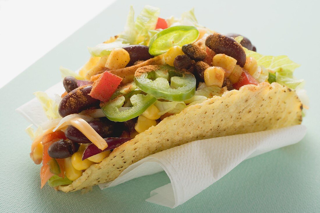 Taco filled with sweetcorn and beans on paper napkin