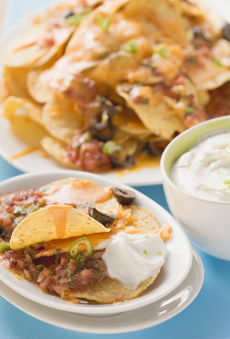Tortilla chips with melted cheese, olives and sour cream