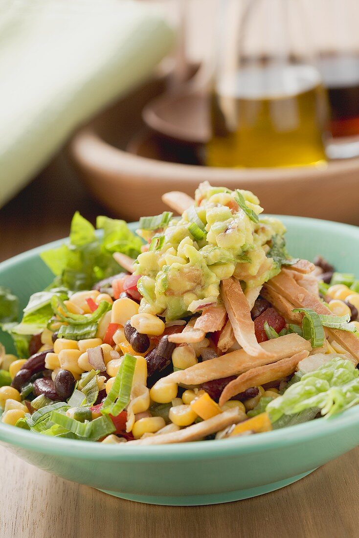 Salat mit Bohnen, Mais, Tortillastreifen und Guacamole