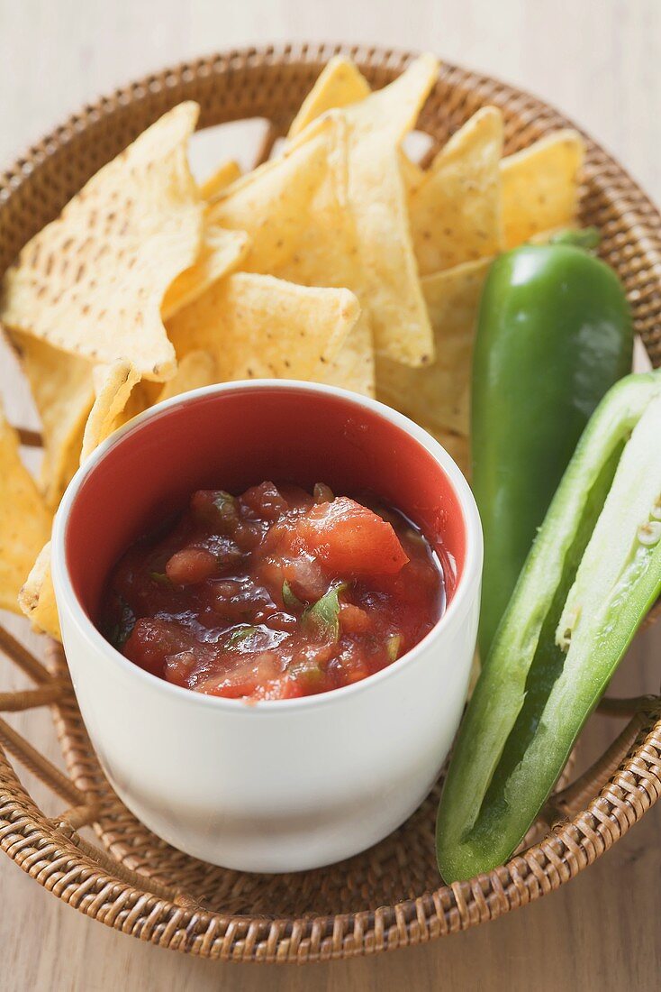 Tomato salsa, nachos and fresh chilli in basket