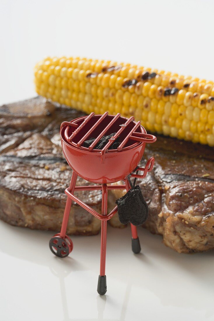 Grilled beef steak with corn on the cob, toy barbecue