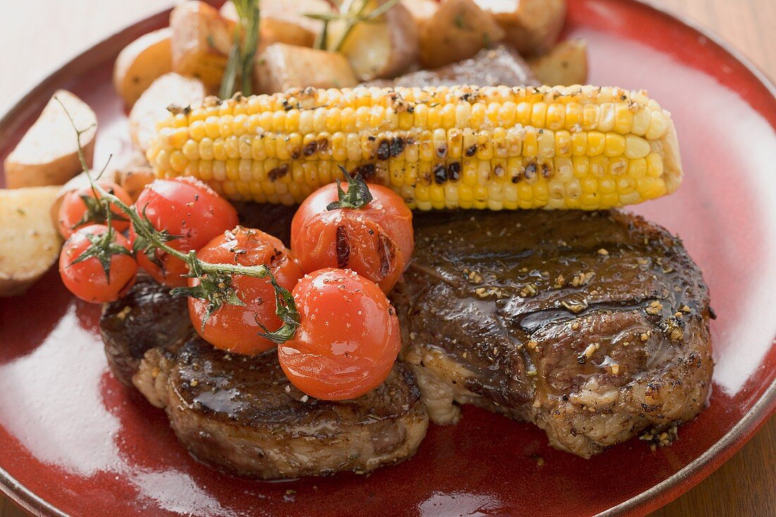 Grilled steak with corn on the cob, cherry tomatoes, potatoes