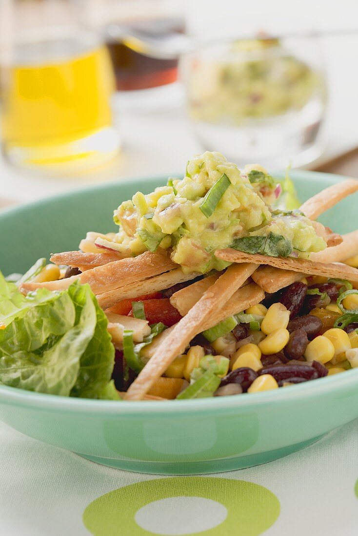 Salat mit Bohnen, Mais, Tortillastreifen und Guacamole