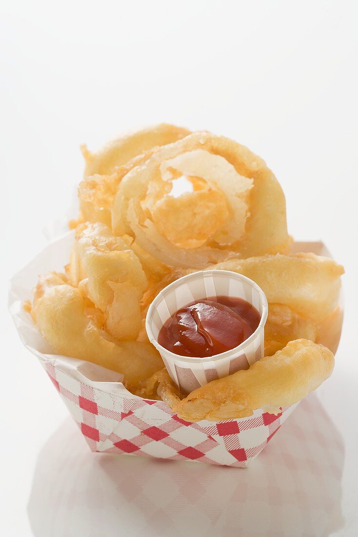 Deep-fried onion rings with ketchup in cardboard container