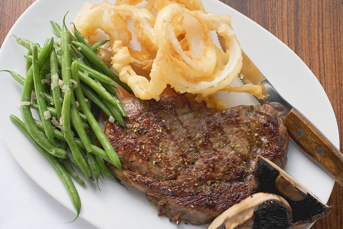 Rib-eye steak with green beans and deep-fried onion rings