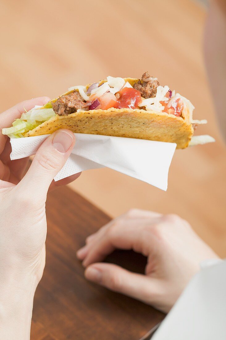 Hände halten Taco mit Hackfleischfüllung