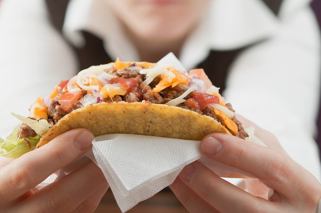 Frau hält Taco mit Hackfleischfüllung