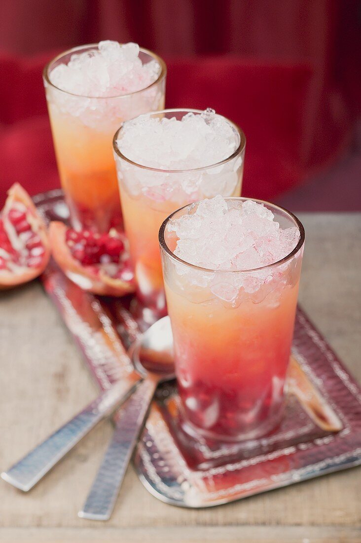Drei fruchtige Drinks mit Orangensaft und Granatäpfeln