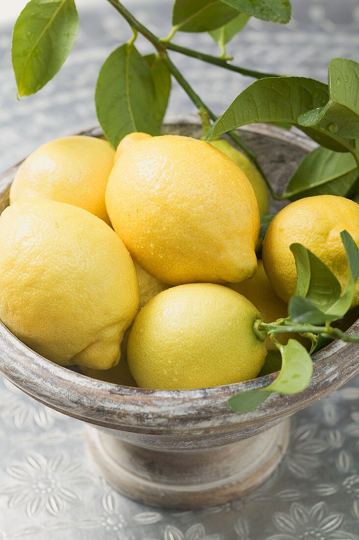 Fresh lemons with leaves in bowl