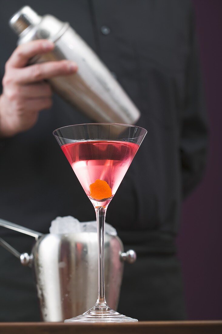 Cosmopolitan in glass, bartender with cocktail shaker