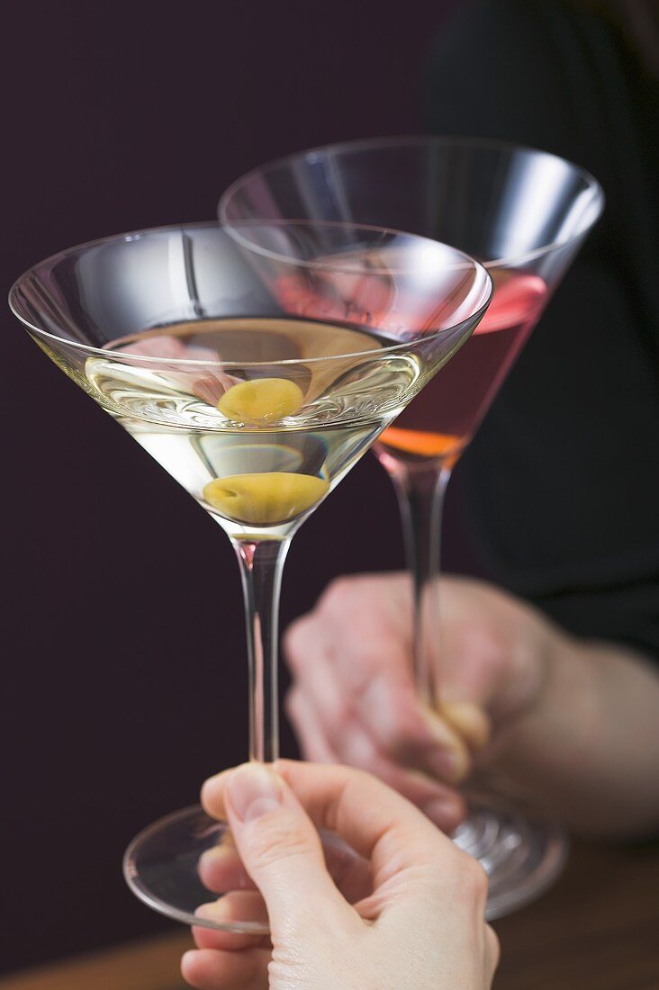 Hands clinking glass of Martini & glass of Cosmopolitan