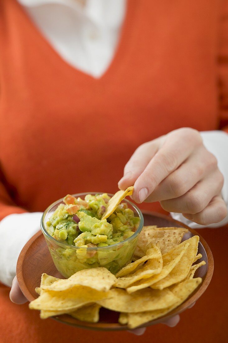 Frau dippt Nacho in Guacamole