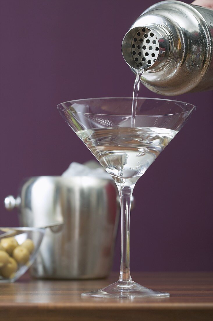 Martini aus Cocktailshaker in Glas gießen