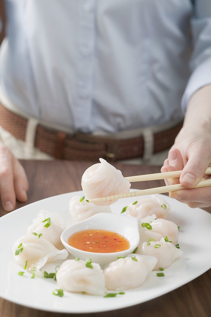 Woman eating dim sum with chilli sauce