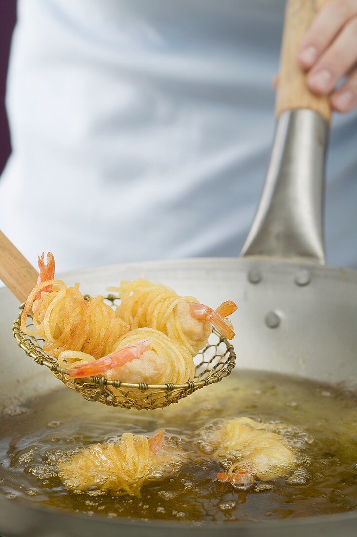 Deep-frying noodle-wrapped prawns in wok