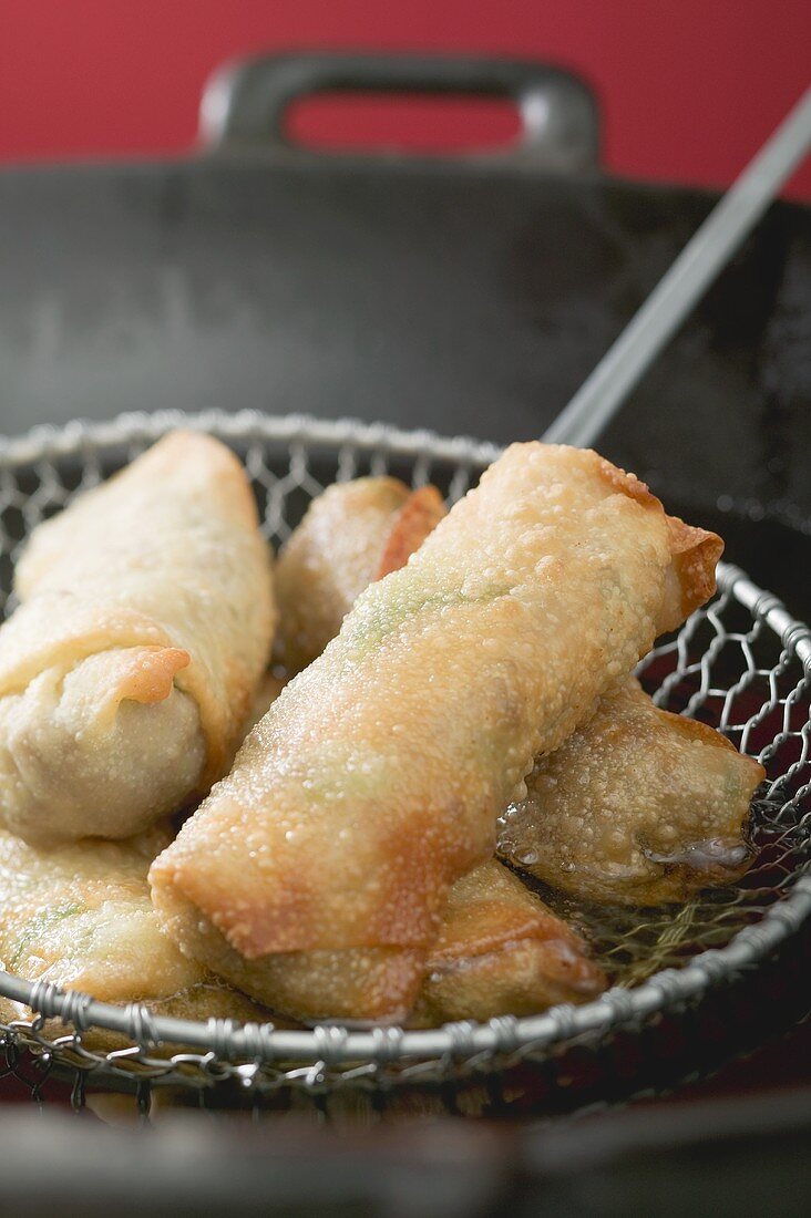 Taking deep-fried spring rolls out of wok