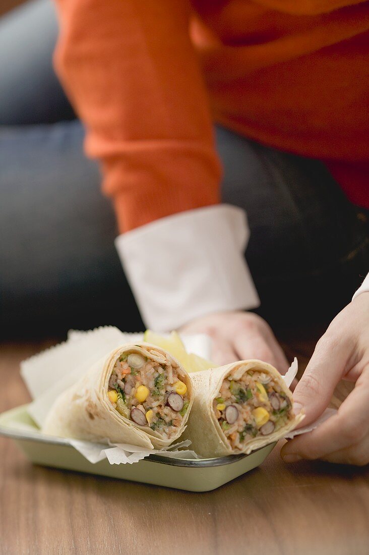 Woman sitting on floor with burritos