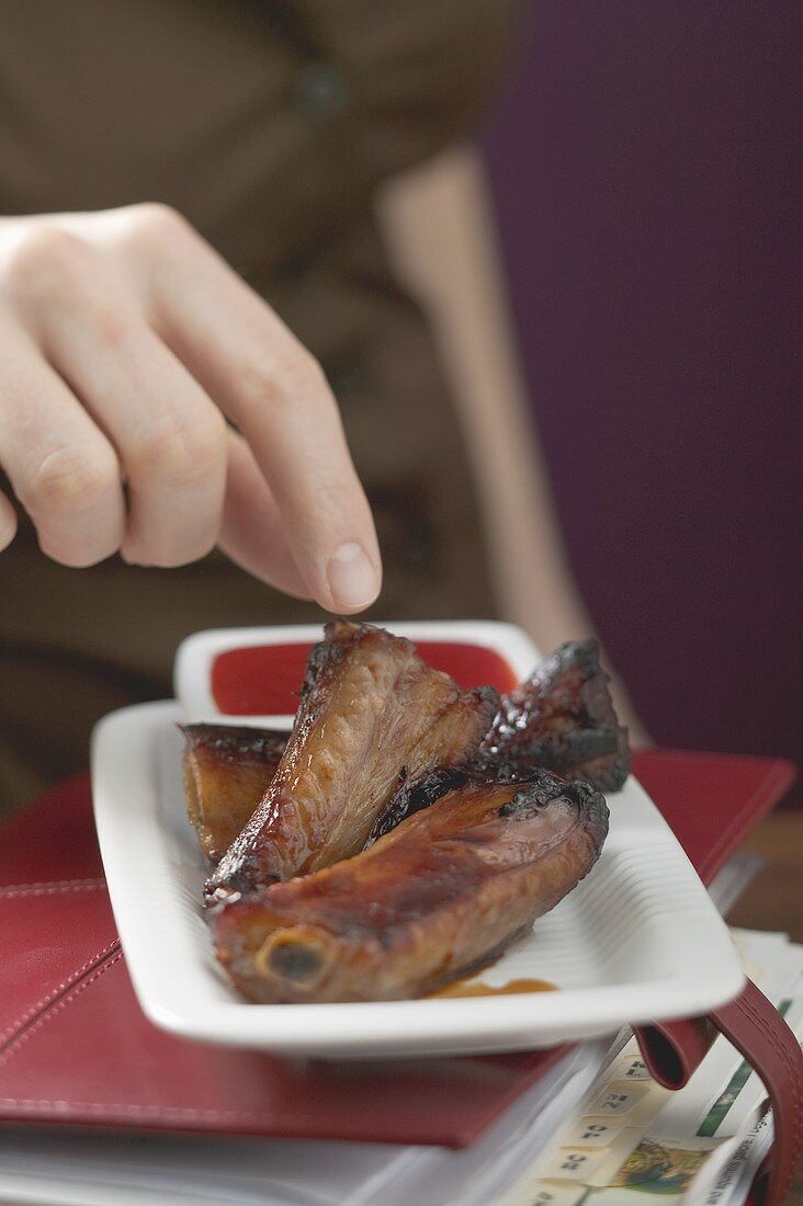 Woman reaching for glazed pork ribs